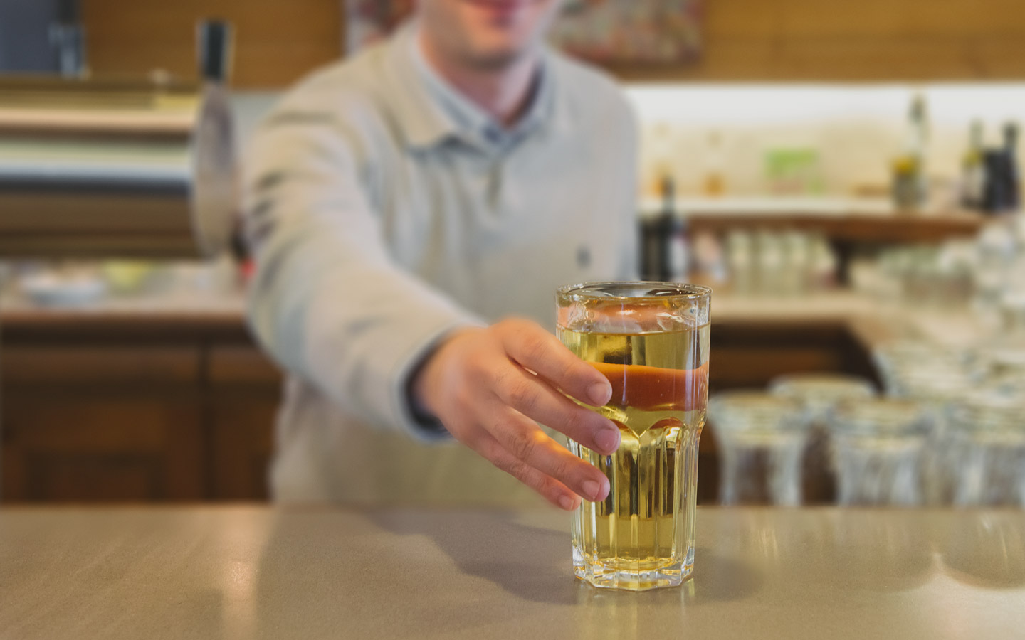 Ein Kellner reicht ein Glas mit Saft über den Tresen